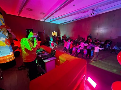 Bunt beleuchteter Raum, Heiko am DJ-Pult und eine Kinderpolonaise unterwegs.